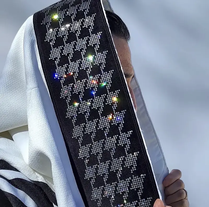 Akiva Hoffmann holding up a black atarah of clear crystal stars in the sun